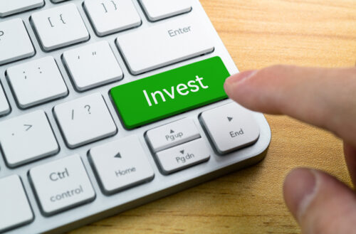 Human hand press the button with word invest