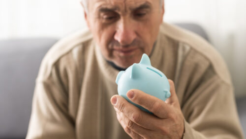 Senior caucasian man holding piggy bank with glasses depressed and worry for distress, crying angry and afraid. sad expression