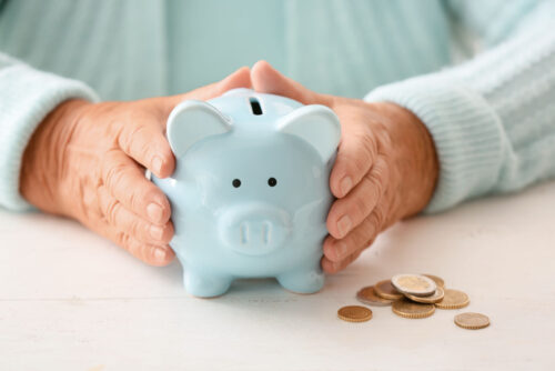 Blue piggybank held in hand of older person.
