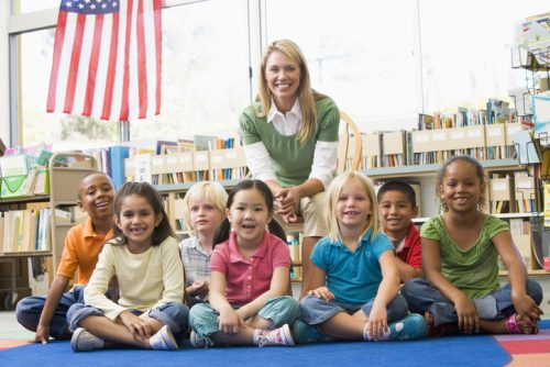 indergarten teacher sitting with children in library