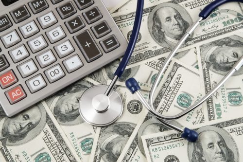 Calculator and stethoscope on banknotes background
