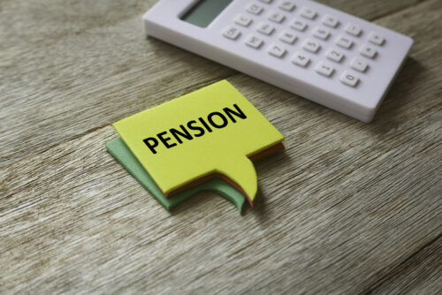 Close-Up of word pension on paper next to a calculator.