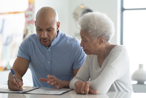 A Male African American Adviser Meets with A Female Senior Client stock photo