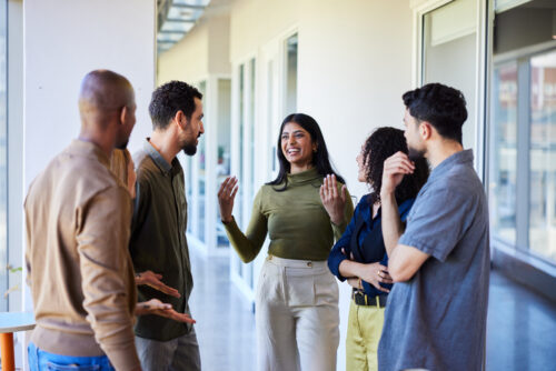 Laughing young businesswoman talking with colleagues in an office hallway