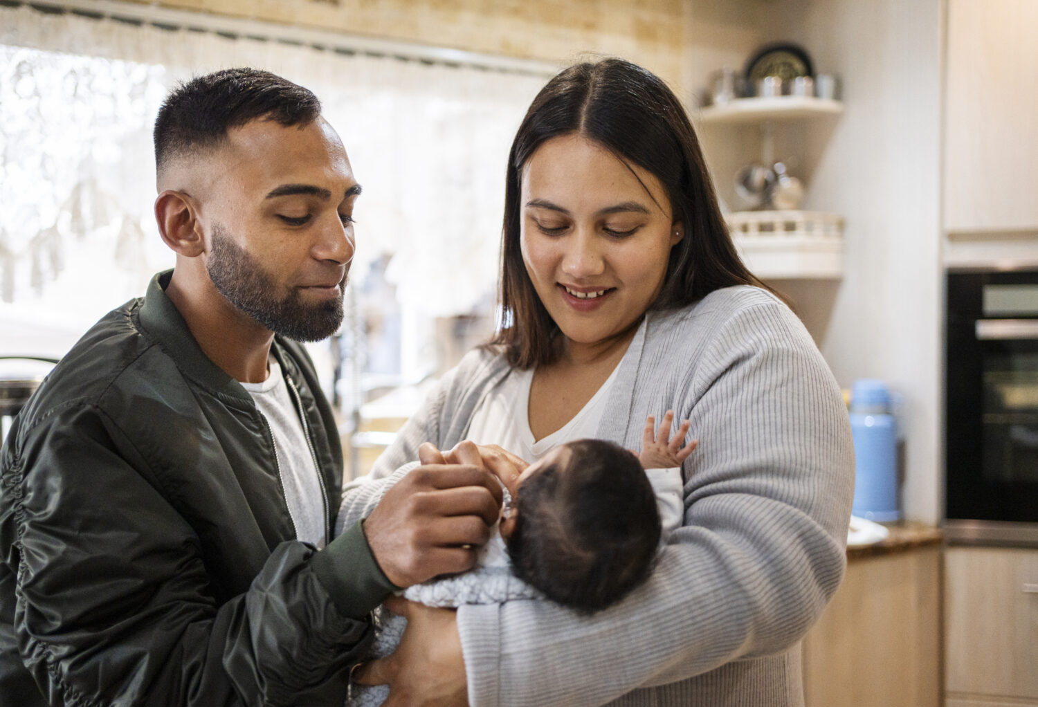 Loving parents standing with their baby girl in their kitchen