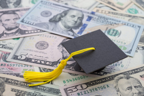Graduation cap university or college degree on US dollars banknotes background.