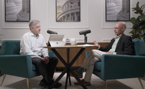 Two men sitting at table for podcast interview.