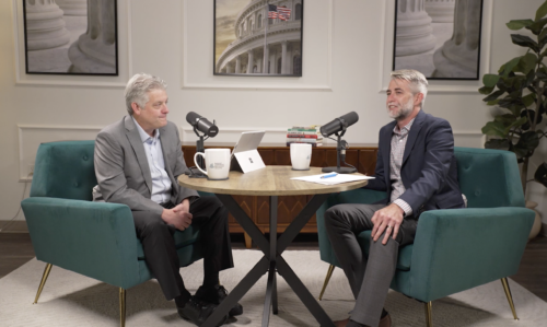 2 men sitting at a table with microphones doing a podcast interview